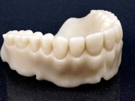 A closeup of 3D printed white teeth prototype on a black tile.